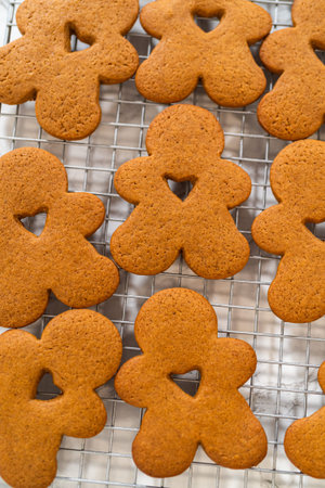 Close-up of golden-brown gingerbread men with heart-shaped cutouts cooling on a wire rack.