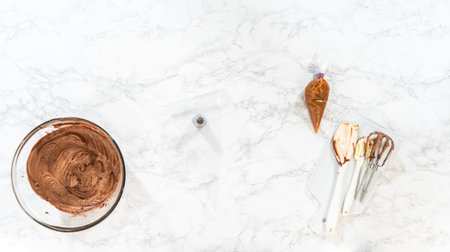 Flat lay. The chocolate icing is carefully transferred into a piping bag, ready to adorn the...
