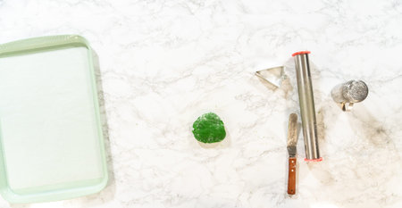 Overhead view of Green Gingerbread Cookies dough, partially rolled out, next to tree-shaped cutouts...