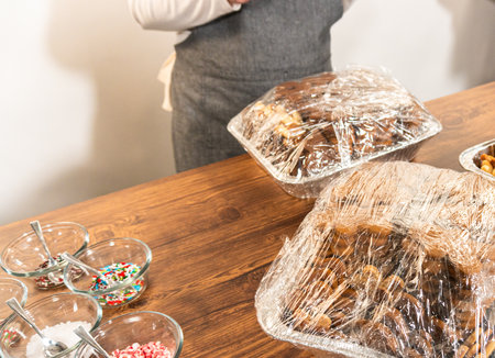 Making gingerbread man cookie sandwiches filled with eggnog buttercream, arrayed on a rustic wooden table, ideal for heartfelt Christmas gifting.の写真素材