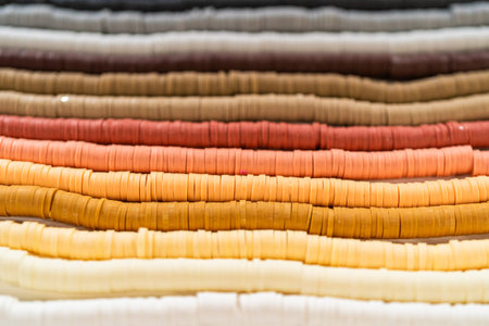 A vibrant collection of clay beads, neatly arranged by color on a white table, ready to inspire...