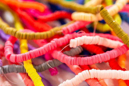 A vibrant collection of clay beads, neatly arranged by color on a white table, ready to inspire...