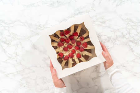Flat lay. With care, the White Chocolate Raspberry Bundt Cake is packaged into a white paper box -...
