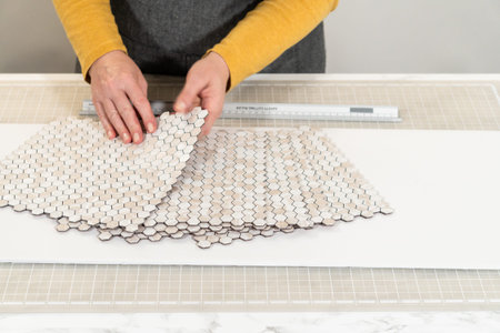 In the process of mounting peel and stick mosaic tiles onto a foam board, perfect for enhancing a food photography studios aesthetic.の写真素材