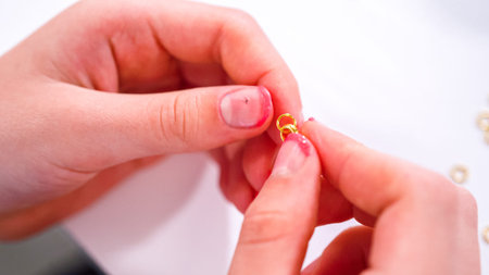 Delicate fingers navigate through a treasure trove of bright, multicolored beads, each compartment...