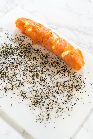 Smoked salmon roll rolled over a mixture of black and white sesame seeds, creating a flavorful and textured coating.の写真素材