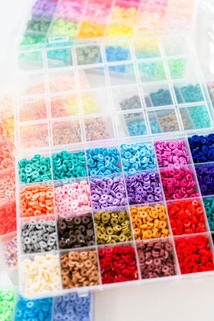 Assorted clay bead boxes neatly arranged on a white table, awaiting a creative kids craft project.