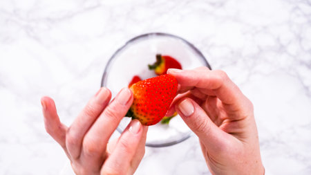 Flat lay. Strawberries, freshly washed and dried, are neatly stored in a glass bowl lined with a paper towel to maintain freshness.の写真素材