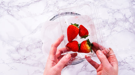 Flat lay. Freshly washed and dried strawberries are carefully arranged in a bowl lined with paper towel, ready for snacking or further use.の写真素材