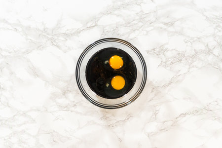 Top view of a glass bowl with molasses and eggs for Spiced Gingerbread Cookie Dough Perfect for Baking. The ingredients are ready to be mixed into the dough, against a marble surface.の写真素材