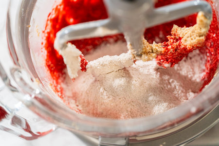 Flour mixture is gradually added to the red batter in the mixing bowl. This step thickens the dough while maintaining its bold red color and rich, spiced aroma for the Classic Red Gingerbread Dough.の写真素材