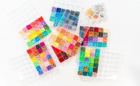 Flat lay. Assorted clay bead boxes neatly arranged on a white table, awaiting a creative kids craft...