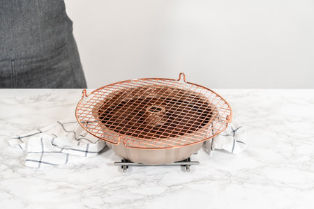 With precision, the Chocolate Bundt Cake is carefully removed from the pan - placed onto a round cooling rack, preparing it for a flawless presentation and delightful indulgence.の写真素材