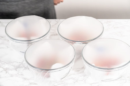 Strawberries, freshly washed and dried, are neatly stored in a glass bowl lined with a paper towel...