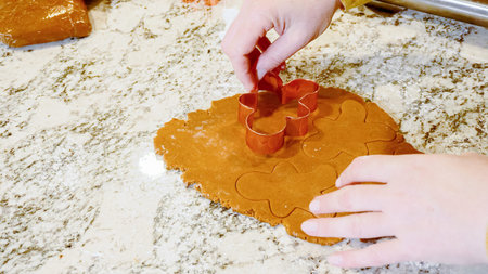 Using various festive cookie cutters, were cutting out charming gingerbread cookies from the rolled...