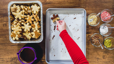 Flat lay. Creating snowflake-shaped cutout sugar cookies, dipped in chocolate, and adorned with...