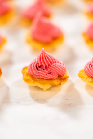 Freshly baked lemon spritz cookies with a swirl of cranberry buttercream piped on top. The vibrant...