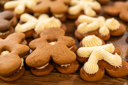 Making gingerbread man cookie sandwiches filled with eggnog buttercream, arrayed on a rustic wooden...