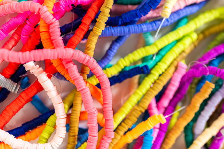 A vibrant collection of clay beads, neatly arranged by color on a white table, ready to inspire...