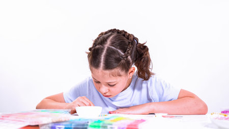 Delicate fingers of a young girl navigate through a treasure trove of bright, multicolored beads,...