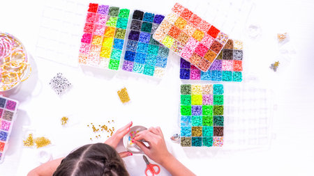 Flat lay. Delicate fingers of a young girl navigate through a treasure trove of bright, multicolored...