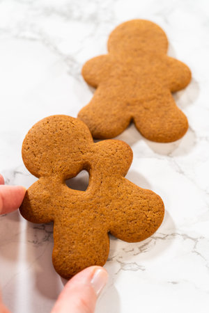 Close-up of a single gingerbread man cookie with a heart-shaped cutout on a white surface.