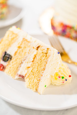 A close-up of a sliced birthday cake focusing on its internal layers, showing fruit, sponge, and...
