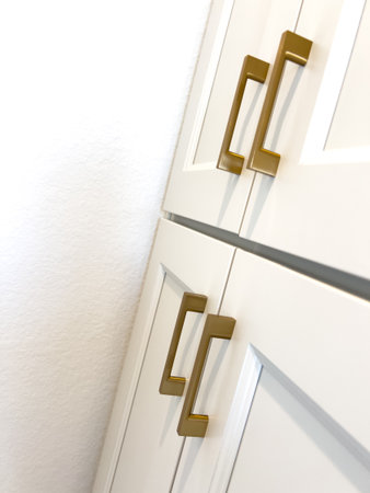 Sleek white cabinets with matte gold hardware, highlighting modern cabinet design. Ideal for use in home decor magazines or remodeling guides.の写真素材