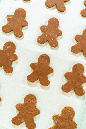Close-up view of a single gingerbread man cookie on parchment paper, highlighting its festive design...