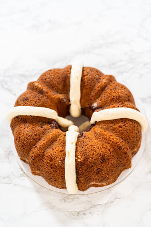 With precision, the White Chocolate Raspberry Bundt Cake is carefully removed from the pan - adorned...