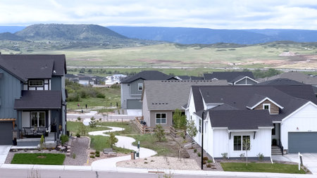 Stylish modern homes built along a curved street in a new Colorado neighborhood. Homes have varying facades and rooftop designs with scenic views.の写真素材