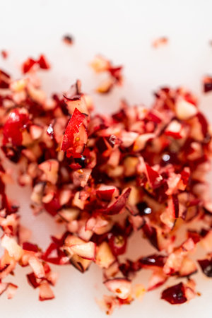 A detailed macro shot of freshly chopped cranberries, revealing their deep red color and juicy texture. The small, uneven pieces highlight their natural tartness and versatility in baking, sauces, and holiday recipes. Perfect for showcasing seasonal ingredients or food preparation techniques.の写真素材
