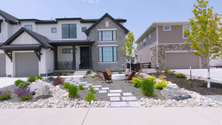 Newly built suburban houses feature landscaped front yards with decorative stone pathways, shrubs,...