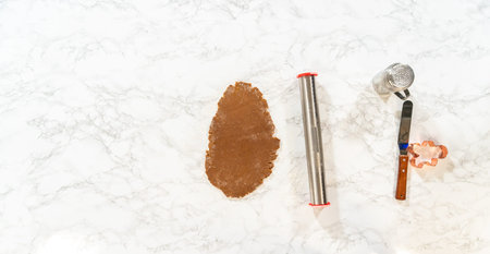 Overhead view of the dough rolling process for Spiced Gingerbread Cookies, showing hands rolling the...