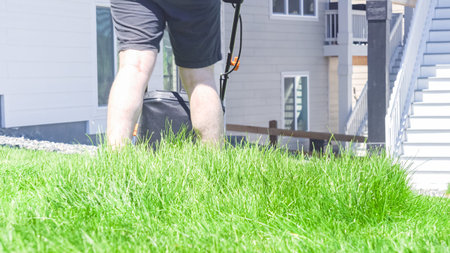 At a residential suburban house, a lush green lawn is meticulously mowed using an electric lawn...