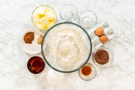 Top view of ingredients for Chocolate Ginger Sugar Cookie Dough on a marble surface, including...