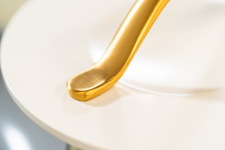 Curved golden handle on elegant white cookware. Designed for upscale marketing visuals or cooking blog imagery.の写真素材
