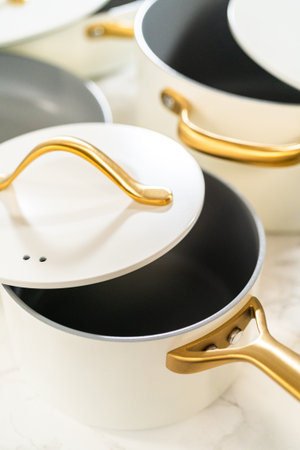 A top-down view of a white ceramic pot with a curved gold handle and matching lid. Great for kitchen product displays or cookware advertisements.の写真素材