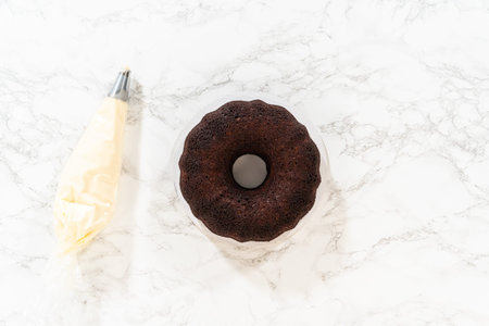 Flat lay. With precision, the Chocolate Bundt Cake is carefully removed from the pan - adorned with luscious cream cheese frosting, creating a delectable treat that is sure to delight.の写真素材