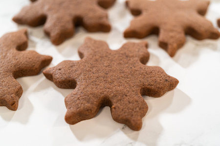 Grouped arrangement of three Chocolate Ginger Sugar Cookies in snowflake shapes on a marble surface,...