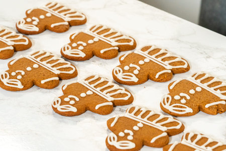 A group of gingerbread girl cookies partially decorated with royal icing, displayed alongside...