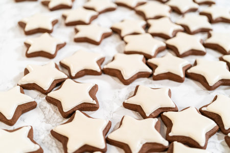 A close-up view of gingerbread star cookies with smooth white royal icing, highlighting the intricate details of the festive cookies.の写真素材