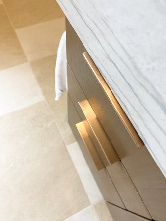 A bathroom cabinet with a marble countertop and metallic handles is shown. The modern design is minimal, clean, and stylish.の写真素材