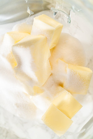Top view of sugar and butter cubes in a mixing bowl, ready to be creamed together as the first step in making Classic Sugar Cookie Dough. The ingredients are positioned for blending, a key step for creating a smooth cookie base.の写真素材