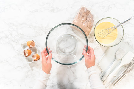 Flat lay. With a hand whisk, the ingredients are expertly mixed in a glass mixing bowl.の写真素材