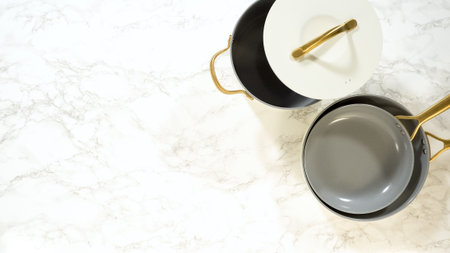 A modern white ceramic cookware set with gold handles is arranged top-down on a marble counter. Lids, pots, and pans form a coordinated layout.の写真素材
