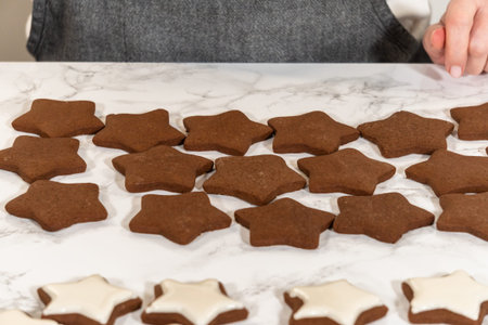 A batch of gingerbread star cookies in various stages of icing, showcasing the step-by-step process...