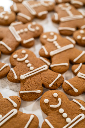 A larger batch of gingerbread man cookies decorated with royal icing, showcasing their cheerful...