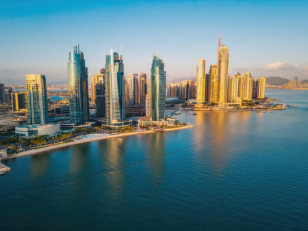 An aerial sunset view of a marina city with tall glass skyscrapers surrounded by calm blue water. The golden light emphasizes the beauty of modern waterfront architecture.の素材