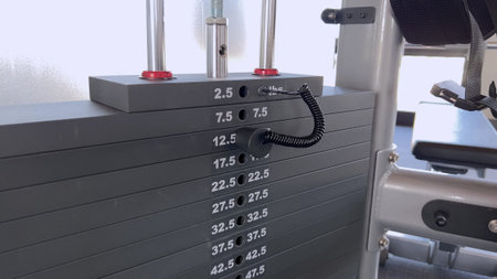 A stack of weights with selection pin on a cable gym machine. The machine is numbered and adjustable...